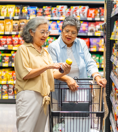 Two older adults read a product label as they shop together at the grocery store. 